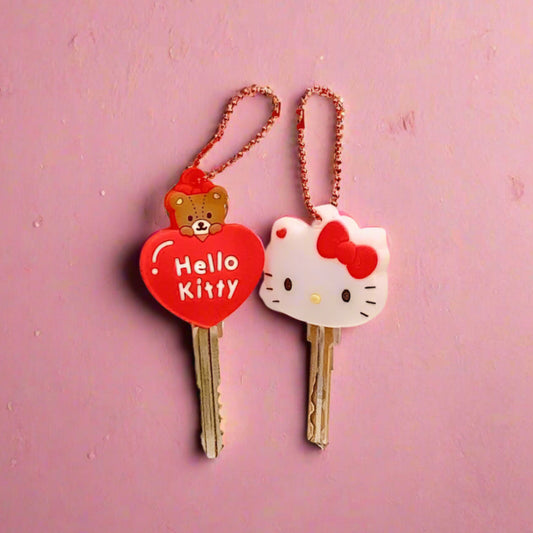 Hello Kitty keychains with a heart-shaped tag on a pink background with cartoon characters.