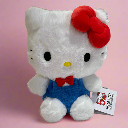 A plush toy of Hello Kitty wearing a blue outfit with a red bow and a keychain attached to it, celebrating the '50th Anniversary' of Hello Kitty.
