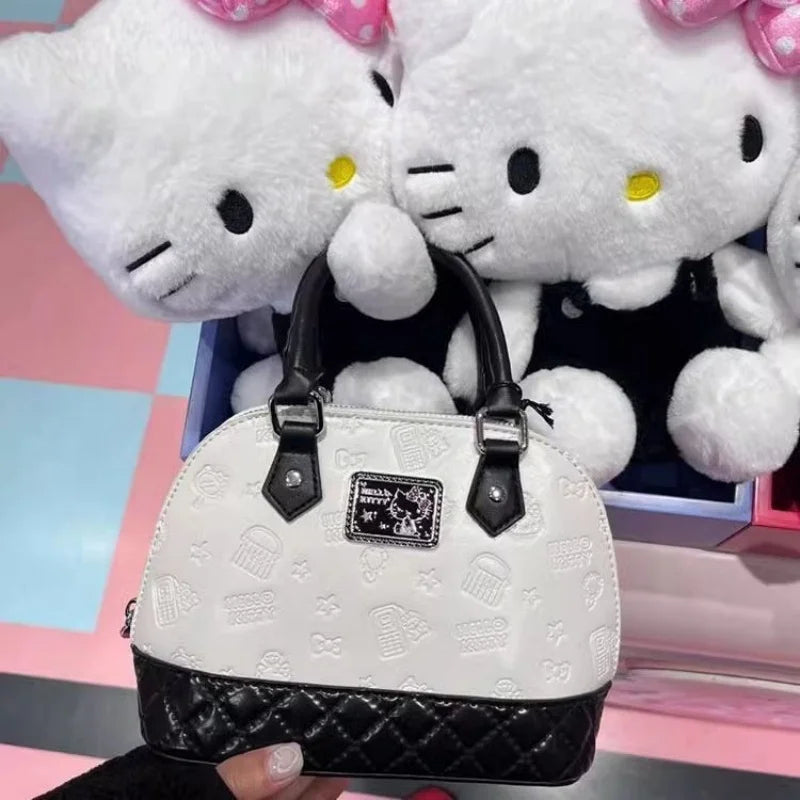 White handbag with black accents held by a person, with two large Hello Kitty plush toys in the background.
