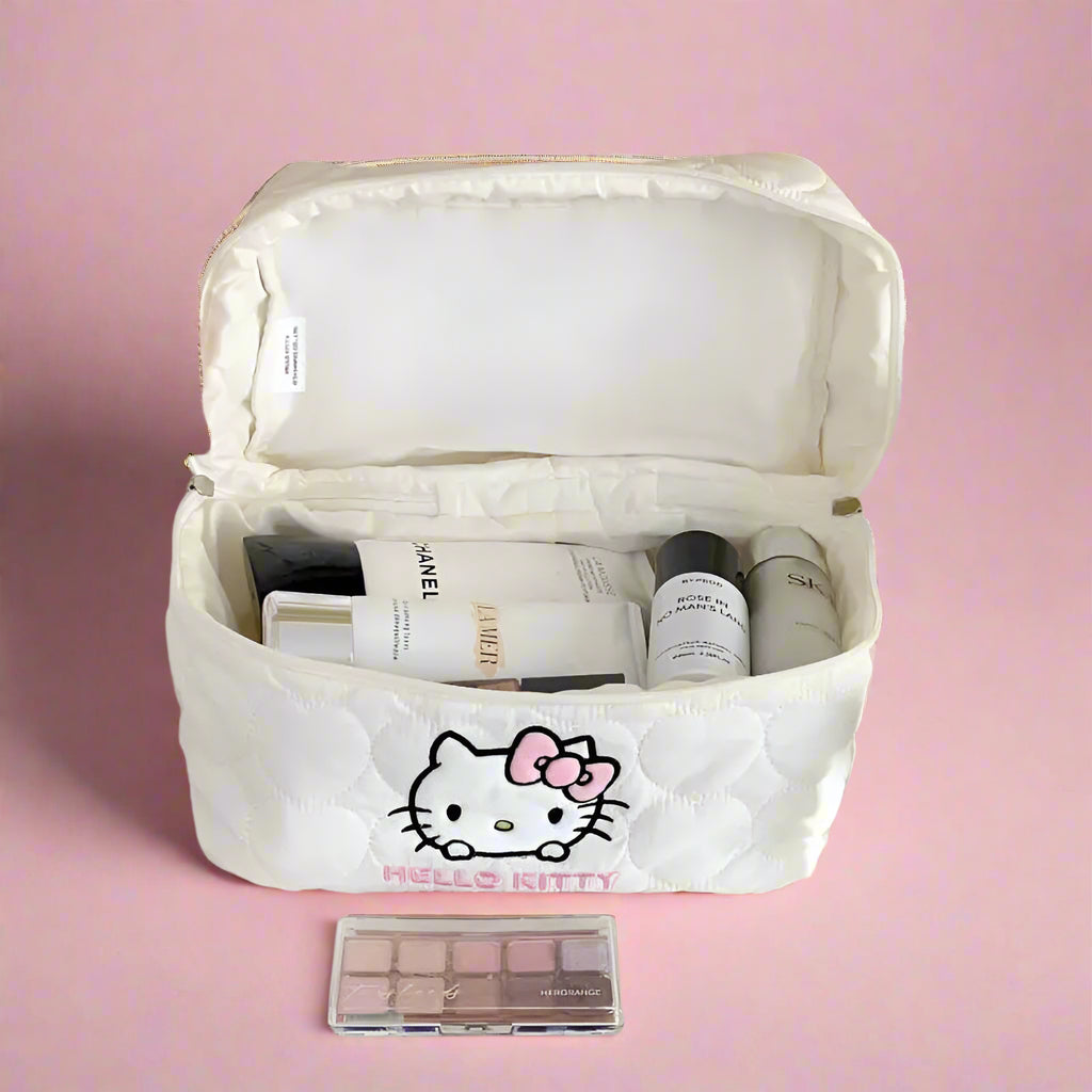 White cosmetic bag with Hello Kitty design containing makeup items on a desk.