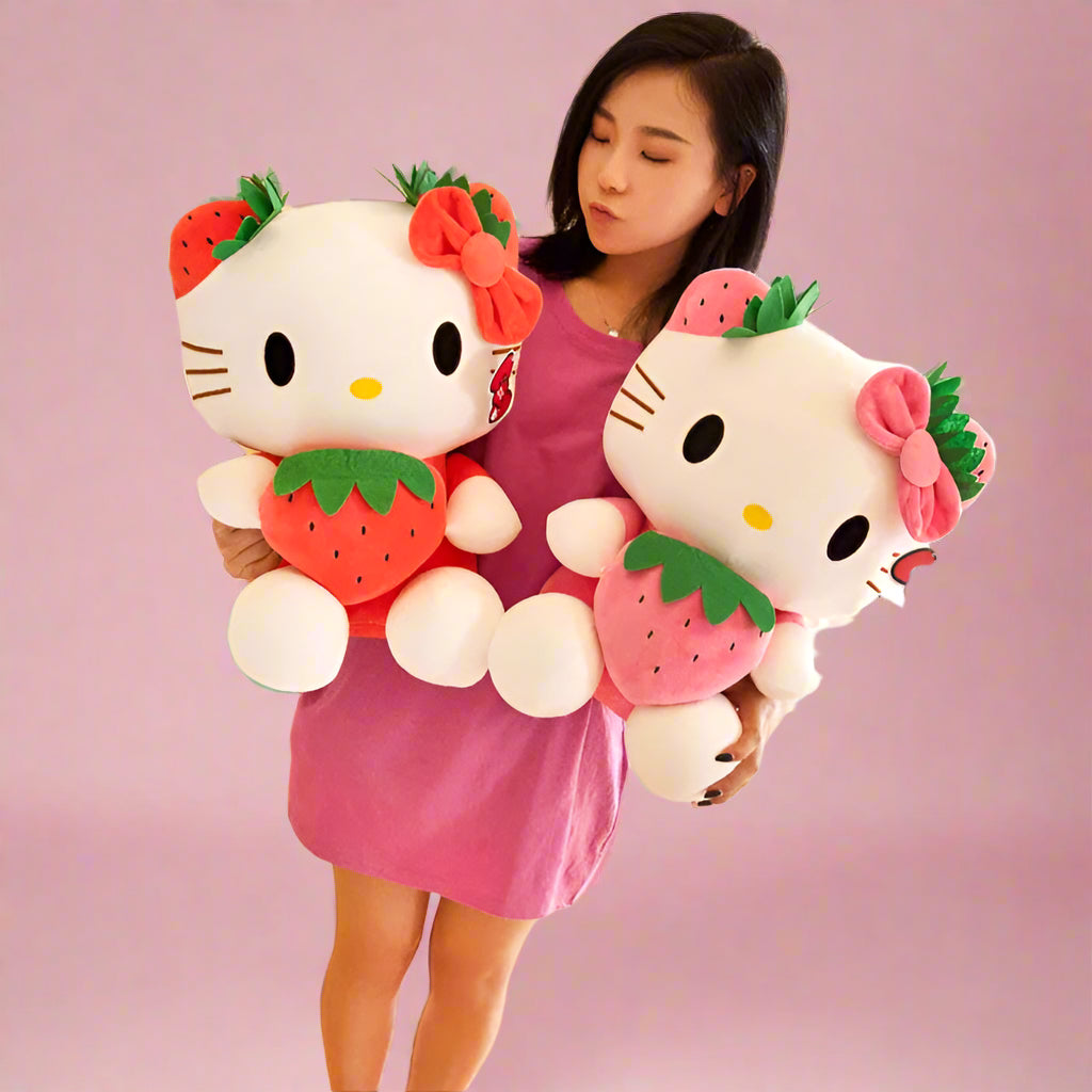 Woman holding two large Hello Kitty plush toys with strawberry designs in a store setting.