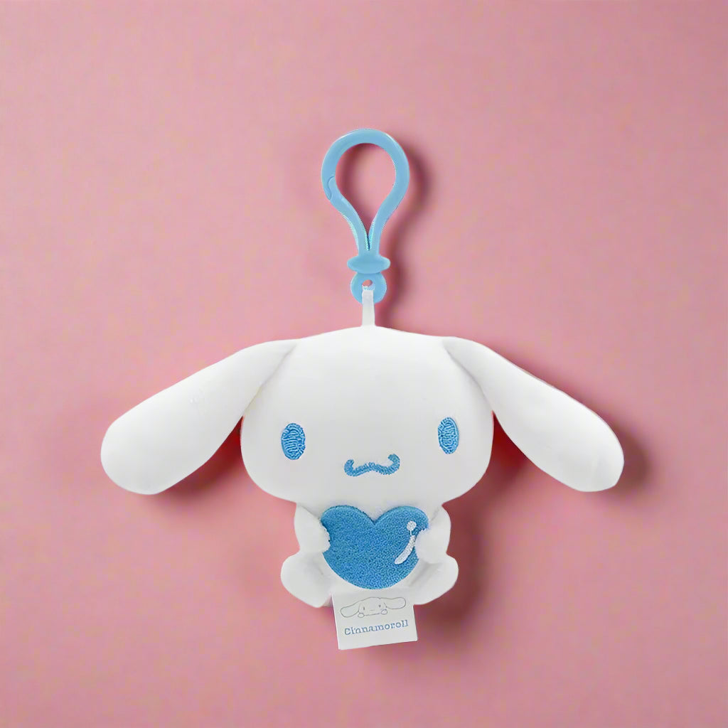 Plush keychain of a white character with blue accents on a light blue background