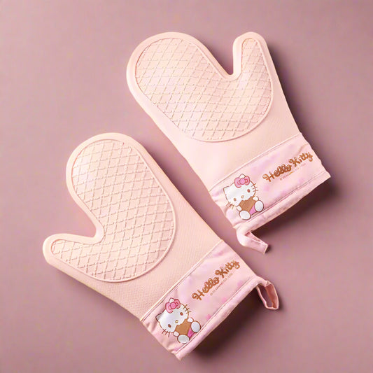 Pink 'Hello Kitty' oven mitt and pot holder on a yellow background with cookies.
