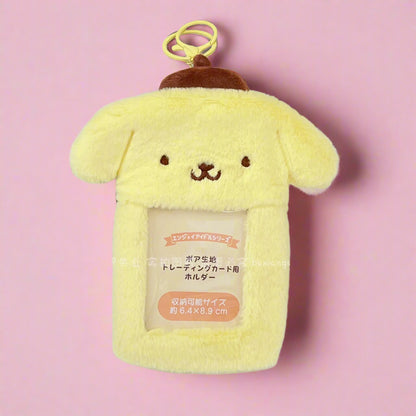 A pink fuzzy photo keychain pendant with a character design, displayed next to a decorated notebook.