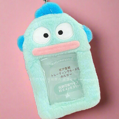 A pink fuzzy photo keychain pendant with a character design, displayed next to a decorated notebook.