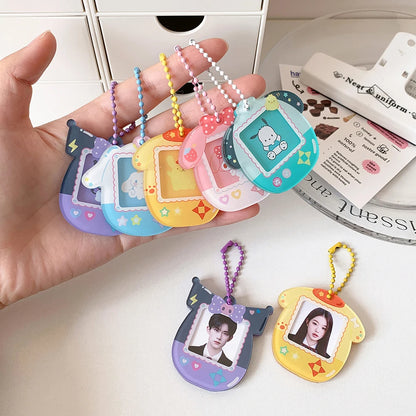 Colorful keychains with character designs held by a hand on a white surface.