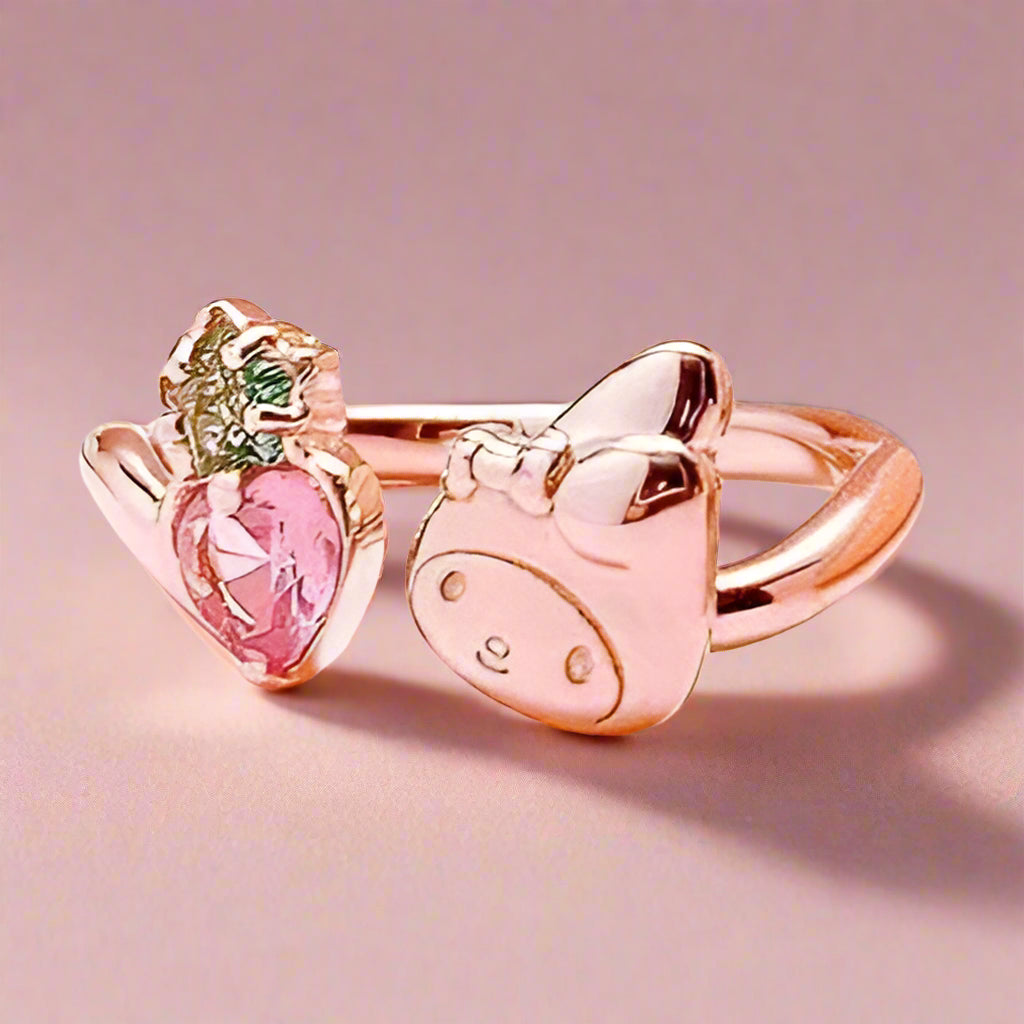 Rose gold ring with pink heart and bow design on a soft pink background with 'My Melody' character and text.