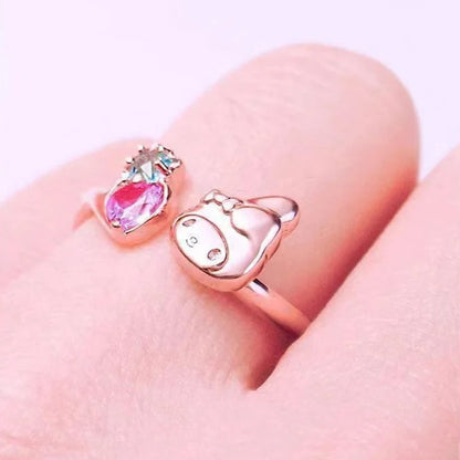 Pink cartoon-themed ring on a hand with decorative flowers in the background