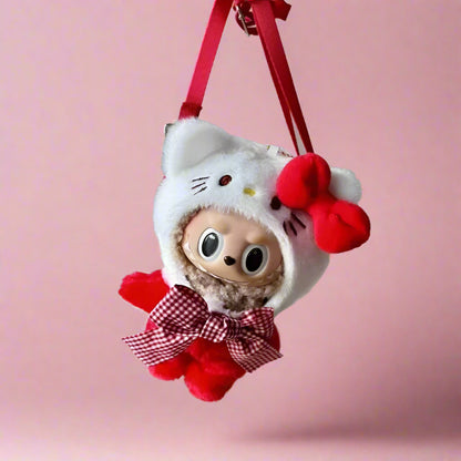 A plush doll wearing a white outfit with red accents, including a bow and a hat resembling a cat, hanging from a red ribbon.